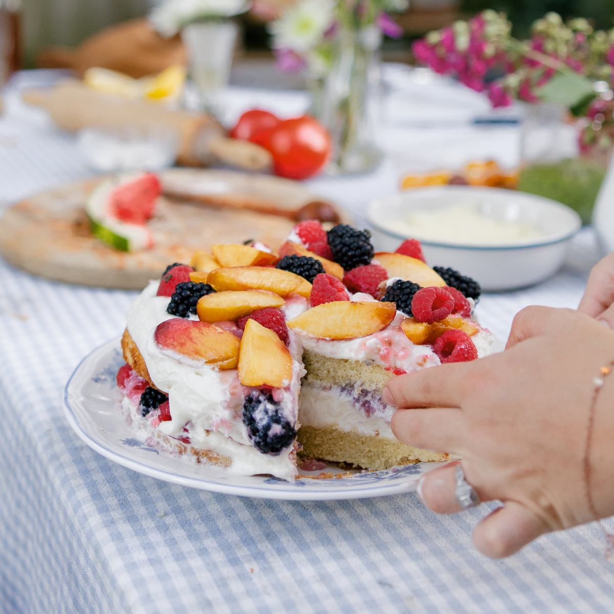homemade raspberry jam and cream cake topped with fresh peaches and berries